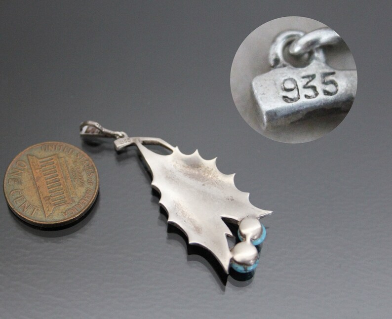Peut inclure: Pendentif en argent sterling avec un motif de feuille de houx et trois pierres turquoise. Le pendentif est marqu&eacute; "935" au dos.