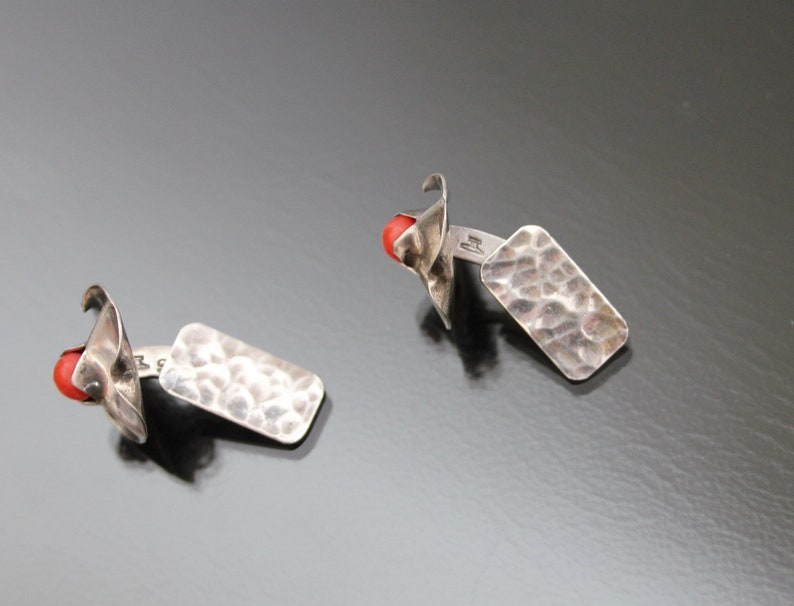 Puede incluir: Un par de gemelos de plata con un dise&ntilde;o rectangular martillado y un acento de piedra roja.