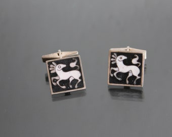 Puede incluir: Un par de gemelos de plata con fondo de esmalte negro y un diseño de caballo estilizado en esmalte blanco.