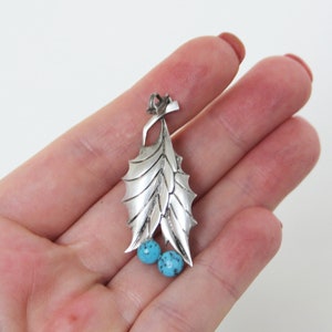 Peut inclure: Pendentif en argent sterling avec un motif de feuille d&eacute;taill&eacute; et deux pierres turquoise.