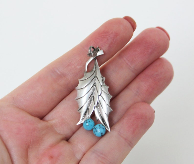 Peut inclure: Pendentif en argent sterling avec un motif de feuille d&eacute;taill&eacute; et deux pierres turquoise.