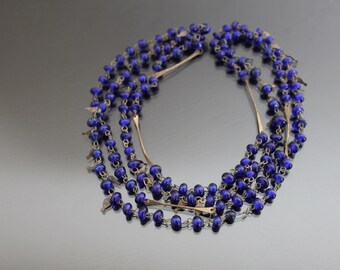 May include: A layered necklace with multiple strands of dark blue glass beads and silver-toned metal accents.