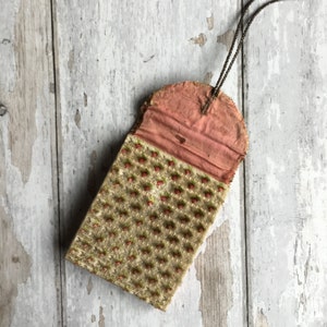 Pode incluir: Uma bolsa de tecido vintage com forro rosa e exterior estampado. A bolsa tem fecho de cord&atilde;o e &eacute; feita de tecido texturizado com design floral.