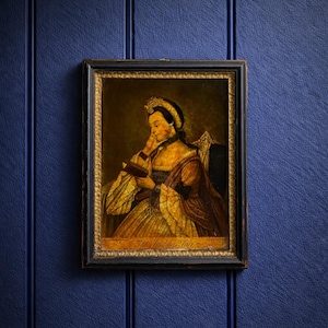May include: A framed portrait of a woman reading a book, dressed in a gold and brown gown, and wearing a crown. The portrait has a black frame with gold trim and is set against a dark blue background.