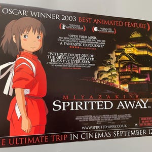May include: A movie poster for Miyazaki's "Spirited Away," featuring a young girl in a red outfit. The poster includes text about the film's awards and release date, with a dark background and a Japanese-style building.