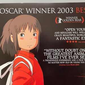 May include: Poster for the animated film, featuring a young girl in a red outfit with white accents. The poster includes text indicating it won an Oscar in 2003 and the Golden Bear award in 2002. Quotes from critics are also featured.