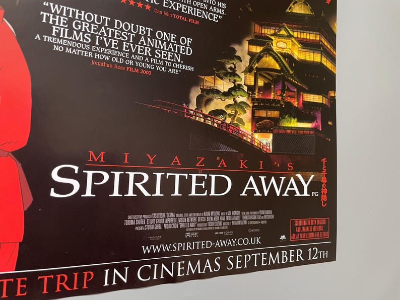 May include: A movie poster for Miyazaki's "Spirited Away" features a dark background with the film's title in large white letters. The poster includes a quote and an illustration of a bridge and buildings.