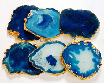 May include: Six blue agate coasters with gold trim. The coasters are round and have a natural, organic shape. They are perfect for adding a touch of elegance to any home.