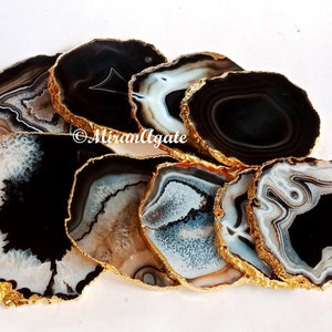 May include: Set of eight agate coasters with gold-plated edges. Each coaster features a unique black and white agate pattern.