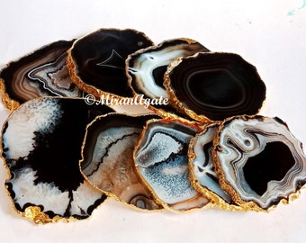 May include: Set of eight agate coasters with gold-plated edges. Each coaster features a unique black and white agate pattern.