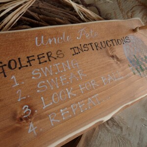 Puede incluir: Un letrero de madera con el texto "Uncle Pete Golfers Instructions" y una lista de instrucciones: "1. Swing 2. Swear 3. Look for ball 4. Repeat..."