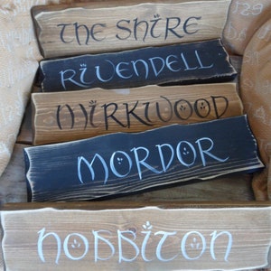 Pu&ograve; includere: Cinque cartelli in legno con lettere bianche, ognuno con un nome diverso dal Signore degli Anelli: La Contea, Gran Burrone, Bosco Atro, Mordor e la Contea degli Hobbit.