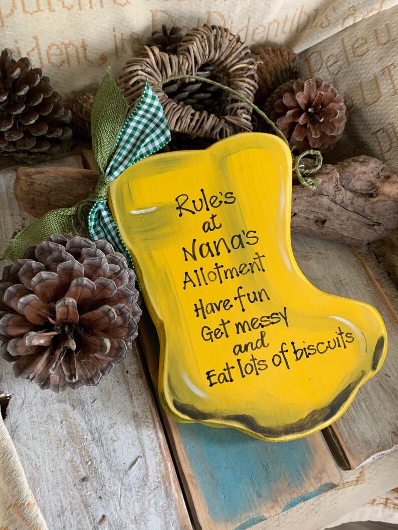 K&ouml;nnte beinhalten: Gelbes Holzschild in Form eines Stiefels mit dem Text "Rule's at Nana's Allotment Have fun Get messy and Eat lots of biscuits".