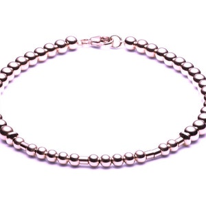 Pode incluir: Um bracelete de contas de ouro rosa com fecho.