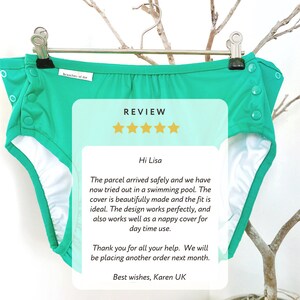 May include: A teal cloth diaper cover with white lining, hanging on a silver hanger. The cover has snap closures and the text "branches of me". A review is overlaid on the image.