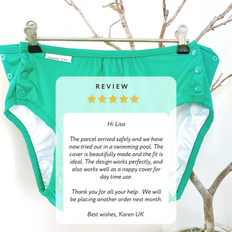 May include: A teal cloth diaper cover with white lining, hanging on a silver hanger. The cover has snap closures and the text "branches of me". A review is overlaid on the image.