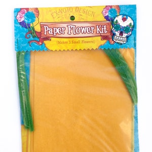 K&ouml;nnte beinhalten: Eine transparente Plastikt&uuml;te mit einem Papierblumen-Bastelset. Das Set enth&auml;lt gelbe Papierquadrate, gr&uuml;ne Pfeifenreiniger und eine bunte Karte mit dem Text "Ex-Voto Design Paper Flower Kit (Makes 3 Small Flowers)" und einer Sch&auml;delabbildung.