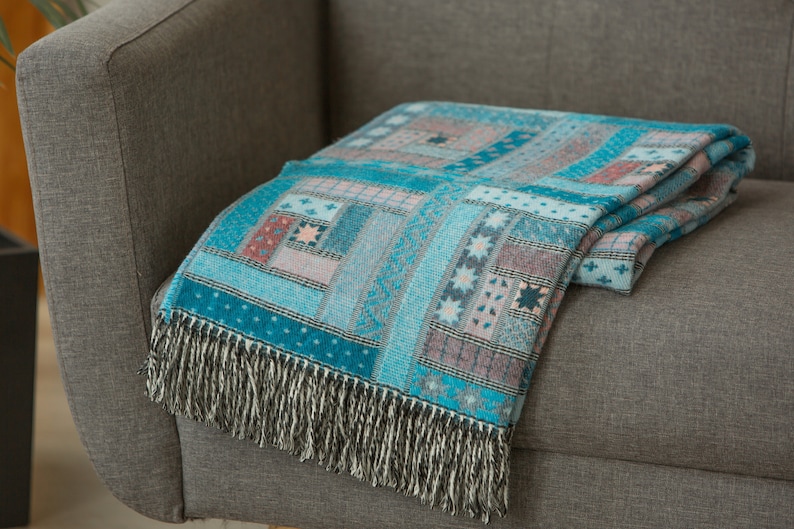 May include: A blue and pink patterned throw blanket with fringe on a grey sofa.