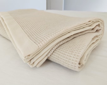 Könnte beinhalten: Eine gefaltete Waffelstruktur-Decke in hellbeige.