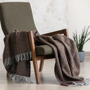 May include: A brown and gray herringbone throw blanket draped over a green armchair with wooden legs.