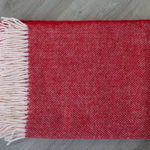 Pu&ograve; includere: Coperta in lana rossa e bianca a spina di pesce con frange.