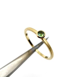 K&ouml;nnte beinhalten: Ein zarter Goldring mit einem kleinen, runden gr&uuml;nen Edelstein.