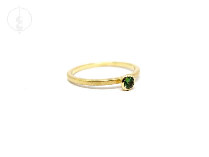 K&ouml;nnte beinhalten: Ein schlichter Goldring mit einem kleinen gr&uuml;nen Edelstein.