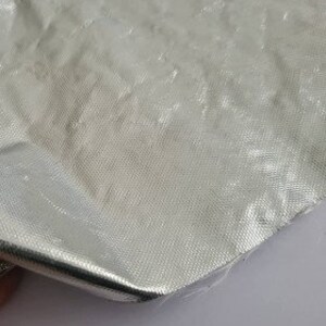 Puede incluir: Una bolsa de aluminio plateada con una superficie texturizada.