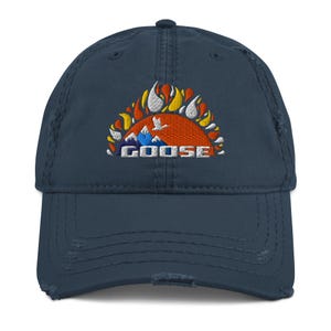 Könnte beinhalten: Eine marineblaue Baseballkappe mit Distressed-Effekt und einem gestickten Design. Das Design zeigt eine stilisierte orangefarbene Sonne mit Flammen, Bergen und einem fliegenden Vogel, darunter das Wort "GOOSE".