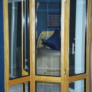 以下が含まれることがあります： 3 つのパネルからなる木製ルームディバイダー。各パネルには鏡面と小さな窓ガラスがあります。ディバイダーは明るい木目調で、青い壁の部屋にあります。