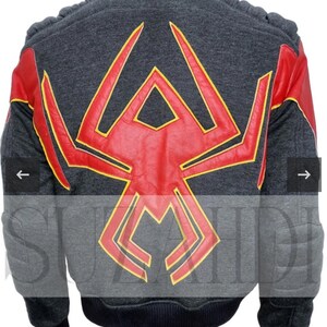 May include: A charcoal gray jacket featuring a large red spider emblem with yellow trim on the back. The jacket has red sleeves with yellow accents, ribbed black cuffs, and a ribbed black hem. The shoulders and elbows have padded detailing.