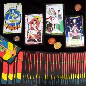 May include: A tarot card reading with ten cards laid out on a black surface. The cards are from the 'The Wild Unknown' tarot deck. The cards are 'The World', 'Queen of Wands', 'Two of Pentacles', 'The Star', and six other cards. There are also three small stones with symbols on them.