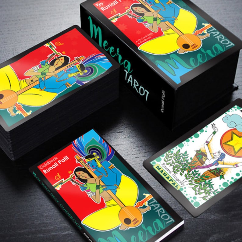 May include: A black box with the text "Meera Tarot" on the front. The box contains a deck of tarot cards with colourful illustrations. The cards feature a variety of characters and symbols, including a woman playing a musical instrument.