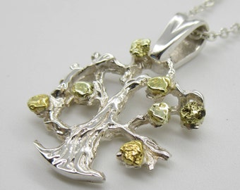 May include: A silver pendant necklace featuring a detailed tree design with gold and green accents. The tree has a textured, organic look and is a popular symbol of growth and life.