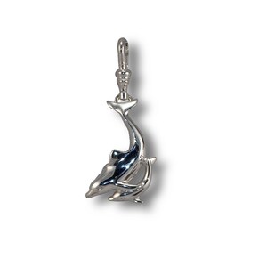 May include: Silver charm featuring two dolphins, one larger than the other, swimming in a playful pose. The charm has a loop at the top for attaching to a bracelet or necklace.