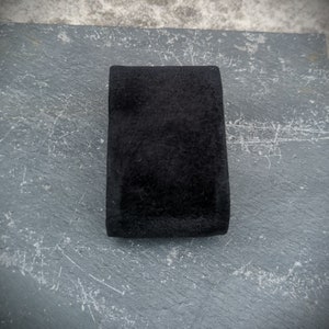 K&ouml;nnte beinhalten: Eine schwarze Schmuckschatulle aus Samt mit einer glatten, weichen Textur.