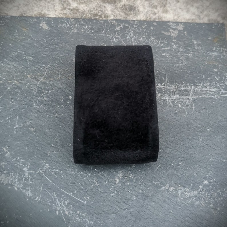 K&ouml;nnte beinhalten: Eine schwarze Schmuckschatulle aus Samt mit einer glatten, weichen Textur.