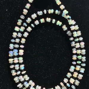 May include: A multi-strand necklace with white opal and black onyx beads. The necklace has a silver clasp.