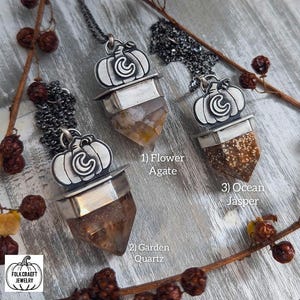 May include: Three silver pumpkin pendants with different crystal points. The pendants are labeled "Flower Agate", "Garden Quartz", and "Ocean Jasper".