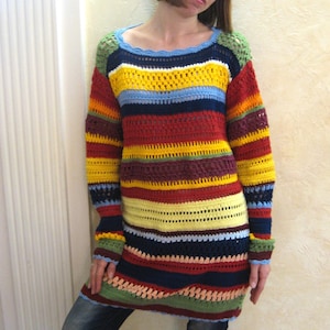 Può includere: Un maglione all'uncinetto a maniche lunghe e multicolore con strisce orizzontali in vari colori, tra cui rosso, giallo, blu e verde. Il maglione ha uno scollo tondo e una vestibilità ampia. Le maniche e l'orlo hanno un design a coste.