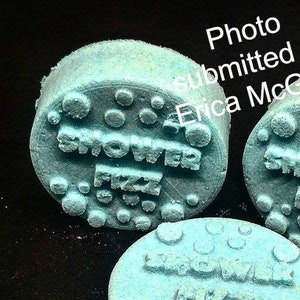 May include: Three round blue shower fizzies with the words "Shower Fizz" embossed on two of them and "Shower Fizz Me" embossed on the third.