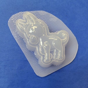 May include: A clear plastic mold for making resin crafts. The mold is shaped like a cartoon donkey with a large head and big ears. The mold is designed to create a 3D donkey figurine.