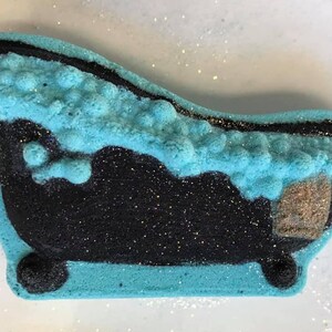Puede incluir: Una bomba de ba&ntilde;o azul y negra con forma de ba&ntilde;era con una parte superior espumosa. La bomba de ba&ntilde;o est&aacute; cubierta de purpurina.