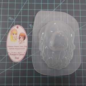 May include: Clear plastic mold of a dog's head, suitable for making soap, candles, or resin crafts. The mold is on a green cutting mat.