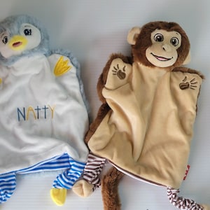 May include: Two plush puppets, one a blue penguin with yellow wings and the word "NATTY" embroidered on the front, and the other a brown monkey with brown and white striped legs.