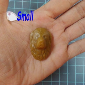 May include: A small, brown, resin dog head sculpture. The sculpture is detailed with fur and facial features.