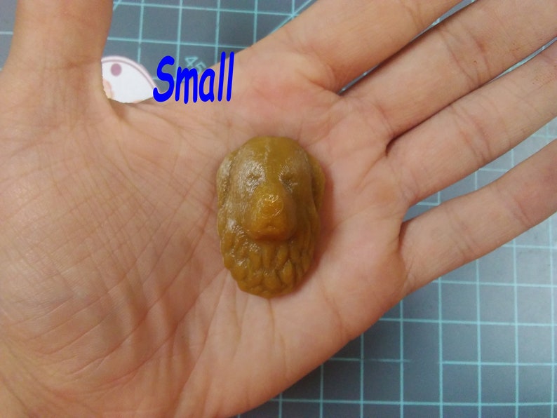 May include: A small, brown, resin dog head sculpture. The sculpture is detailed with fur and facial features.
