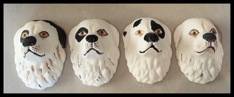 May include: Four ceramic dog head sculptures with black and white markings. The sculptures are painted with brown and orange accents around the eyes and nose.