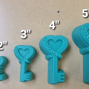 Peut inclure: Cinq moules à clés en forme de cœur bleu sarcelle de différentes tailles, allant de 2,5 cm à 12,7 cm. Les moules présentent un design de cœur détaillé avec une chaîne et des volutes.
