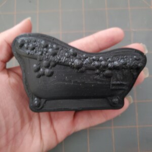 Puede incluir: Una peque&ntilde;a ba&ntilde;era negra con un dise&ntilde;o decorativo alrededor del borde. La ba&ntilde;era est&aacute; hecha de pl&aacute;stico liso y duro.